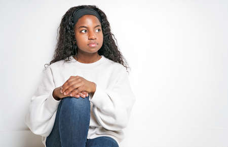Young African Woman sit and pensive On White Background