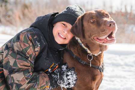 Portrait of little boy with labrador dog in winter season