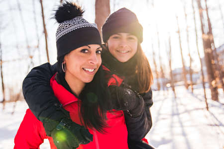 portrait of mother with his teen girl while enjoying outdoors in winterの写真素材