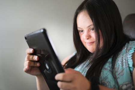 Portrait of trisomy 21 adult working on tablet