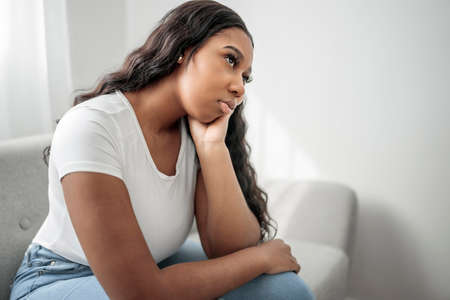 Stressed miserable black woman suffer from grief problem, depressed lonely upset african girl crying alone on sofaの写真素材
