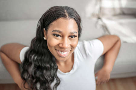 Attractive young African woman sitting on the couch at home