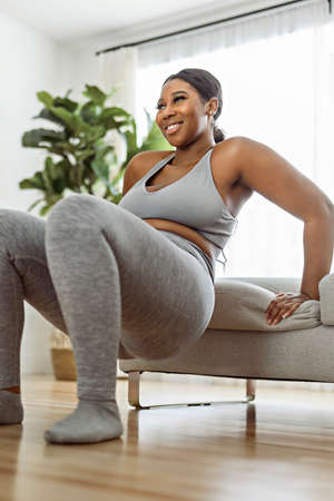 African american woman working out in home livingroom gym
