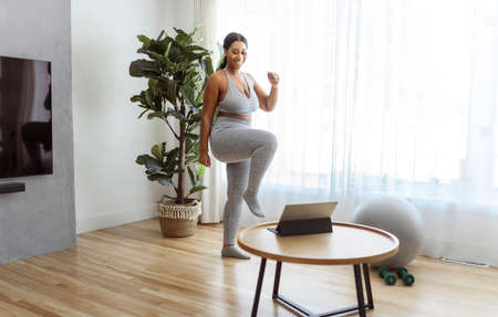 African american woman working out in home livingroom gymの写真素材
