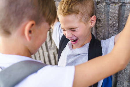 Cruel teenagers punching younger boy, physical intimidation, school bullying