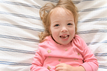 Portrait of cute adorable smiling laughing white Caucasian two years girl on bed