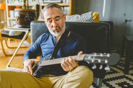A attractive and relaxed looking man playing the guitar