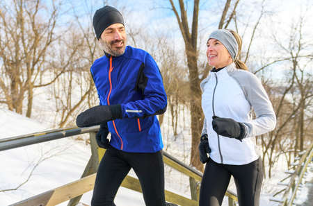 mature couple in the winter running on stairs together in nature