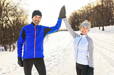 mature couple in the winter running together in nature giving an high five with there handの写真素材