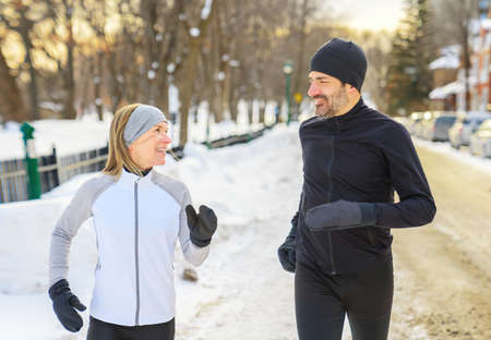 mature couple in the winter running together in urban cityの写真素材