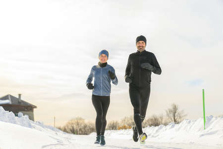 mature couple in the winter running together in natureの写真素材