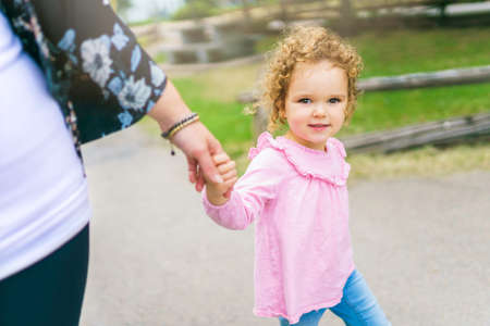 nice mother having fun in summer forest with his child girl holding handの写真素材