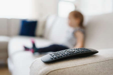 cute little girl watching tv at homeの写真素材