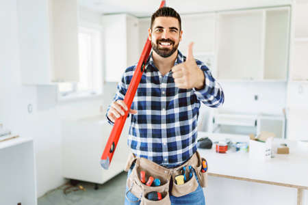 Concentrated young man work with white cabinet in the kitchen with level