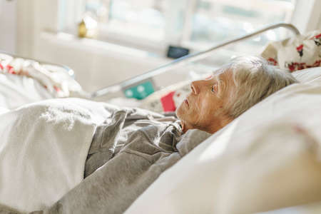 Sick, elderly senior woman in a hospital bed