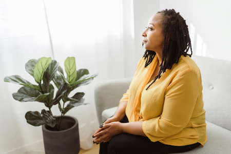 Portrait of an african woman sit on the sofa look worryの写真素材