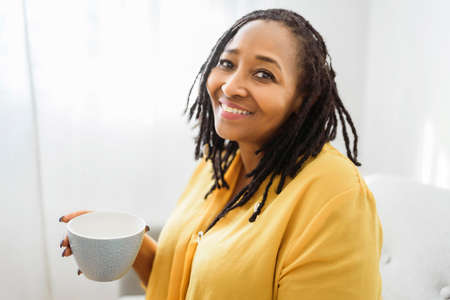 Portrait of an african woman sit on the sofa with coffee