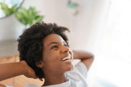 young African female relaxing on a chair in the kitchenの写真素材