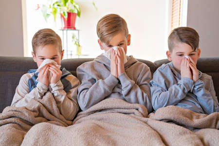 coughing little brothers boys at home having flu on the sofaの写真素材