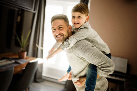 Father or godfather having fun on the living room At Home on his backの写真素材