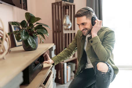 Handsome guy wearing headphones enjoys music in front of his stereo systemの写真素材