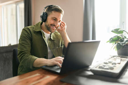young man worker employee with wireless headphones and laptop in front of is office tableの写真素材