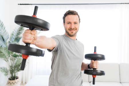 Attractive Fit man Exercise at home on the living room with dumbell on hand