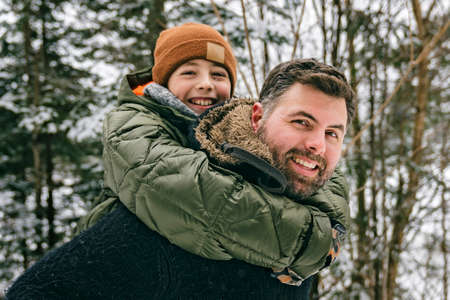Handsome dad and his son are having fun outdoor in winterの写真素材