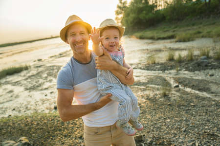 Father have fun with baby on the beach at the sunset