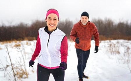 Runner couple jogging in park in warm winter sports clothingの写真素材