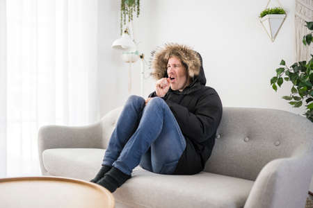 Man cough With Warm Clothing Feeling The Cold Inside House on the sofaの写真素材