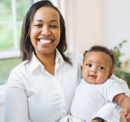 young African woman playing with his little baby on the bedroom