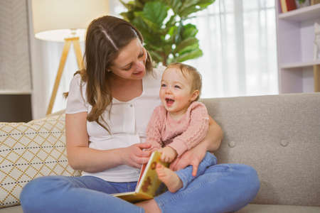 A Young mother is reading a book to her cute daughter.