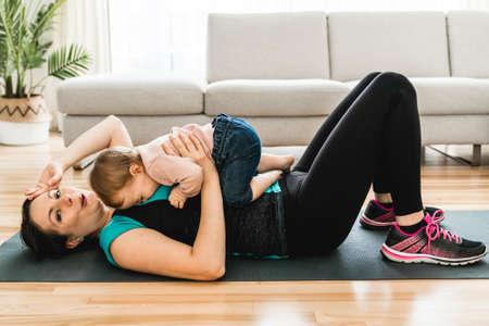 tired mother training with his baby the baby looks at someone.の写真素材