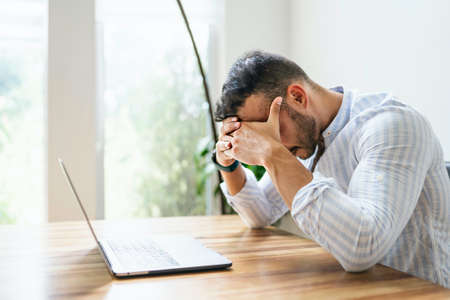 Portrait of a sad and depress mexican businessman working at modern home office with computer laptop
