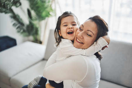 Mother with her daughter having fun in living room at homeの写真素材