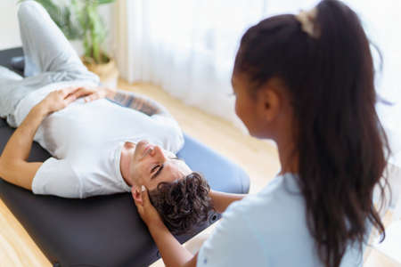 black rehabilitation woman physiotherapy at physio clinic with customerの写真素材