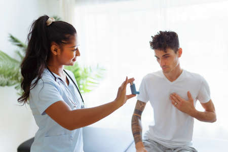 man using inhaler during asthmatic attack with doctor