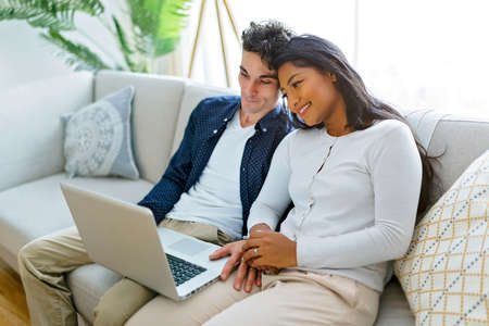 Young couple relaxing on sofa with laptop
