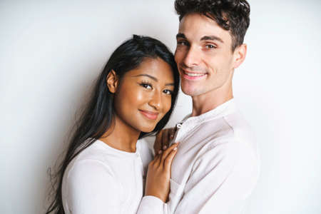 young couple standing together posing in studio white backgroundの写真素材