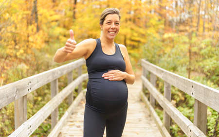 Fit pregnant woman standing outside on a sunny dayの写真素材