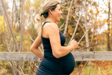 Fit pregnant woman standing outside on a sunny dayの写真素材