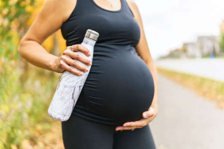 Fit pregnant woman standing outside on a sunny dayの写真素材