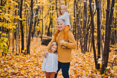 Happy father and daughter in autumn park lying on yellow leavesの写真素材