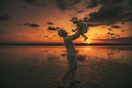 happy family at the beach a father and baby daughter having fun at sunsetの写真素材