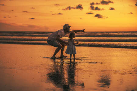 happy family at the beach a father and baby daughter having fun at sunsetの写真素材