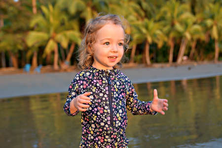 little adorable girl 2 years joyfully on the beach in sunset on holiday
