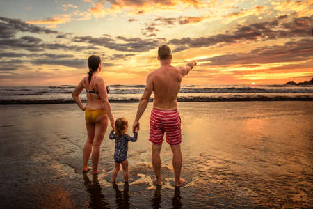 Family on the beach concept, Caucasian family playing and carrying his daughter on the tropical beach in sunset.の写真素材