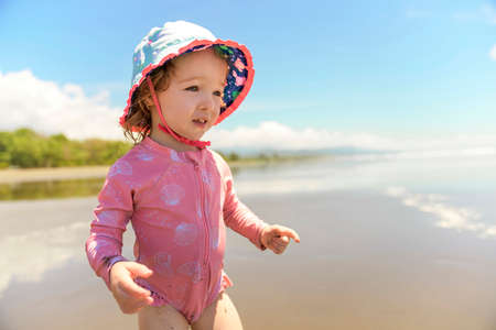little adorable girl 2 years joyfully on the beach in sunset on holiday