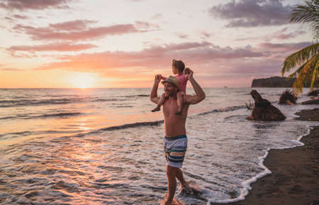 happy family at the beach a father and baby daughter having fun at sunsetの写真素材